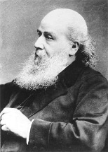 Black-and-white, 19th-century profile photo of a bald white man with a long white beard wearing a dark suit.